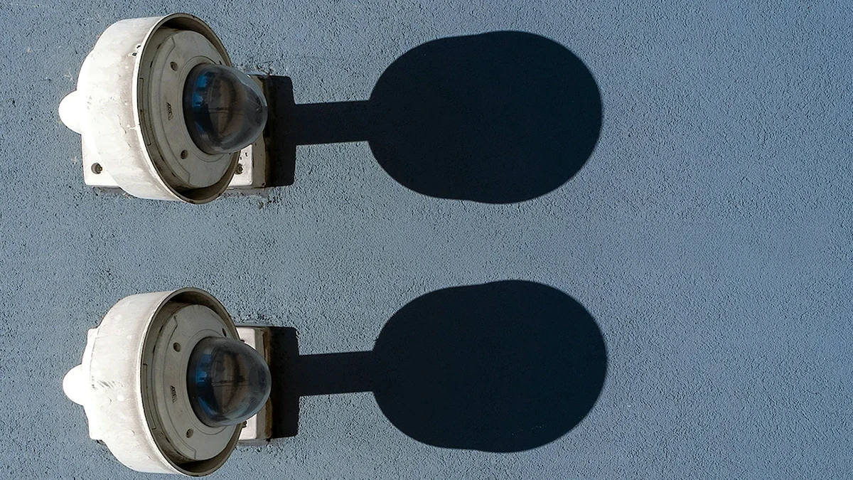 Dos cámaras de seguridad con sombras proyectadas sobre una pared, acompañadas del texto sobre la importancia de los convenios para evitar la doble tributación, reflejando el enfoque preciso y detallado de InvestaTrust en este servicio.