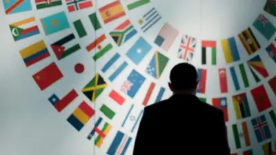 Silueta de una persona frente a múltiples banderas, representando la comparación de jurisdicciones internacionales.
