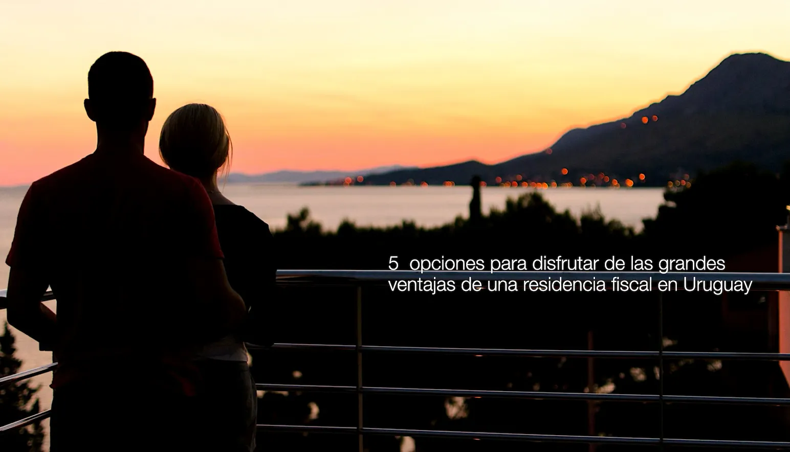 Pareja observando el atardecer desde un balcón con vista al mar, ilustrando las oportunidades de disfrutar las ventajas fiscales de una residencia en Uruguay para empresas de software, trading y holding.